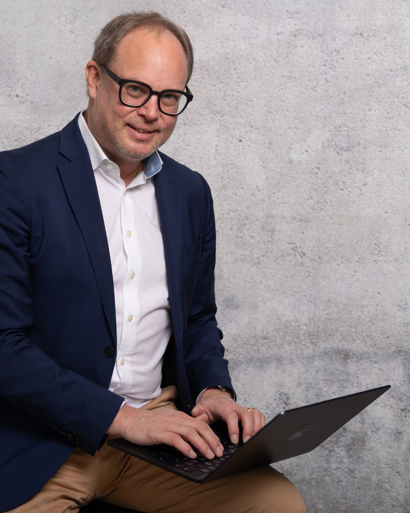 Christian Butz arbeitet an einem Laptop vor Betonwand